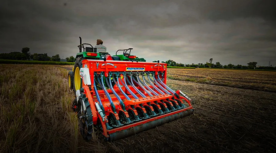 A modern seed drill attached to a tractor, preparing the field for planting