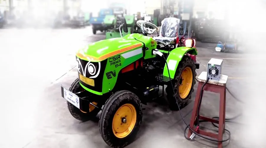 Green electric tractor charging in a workshop